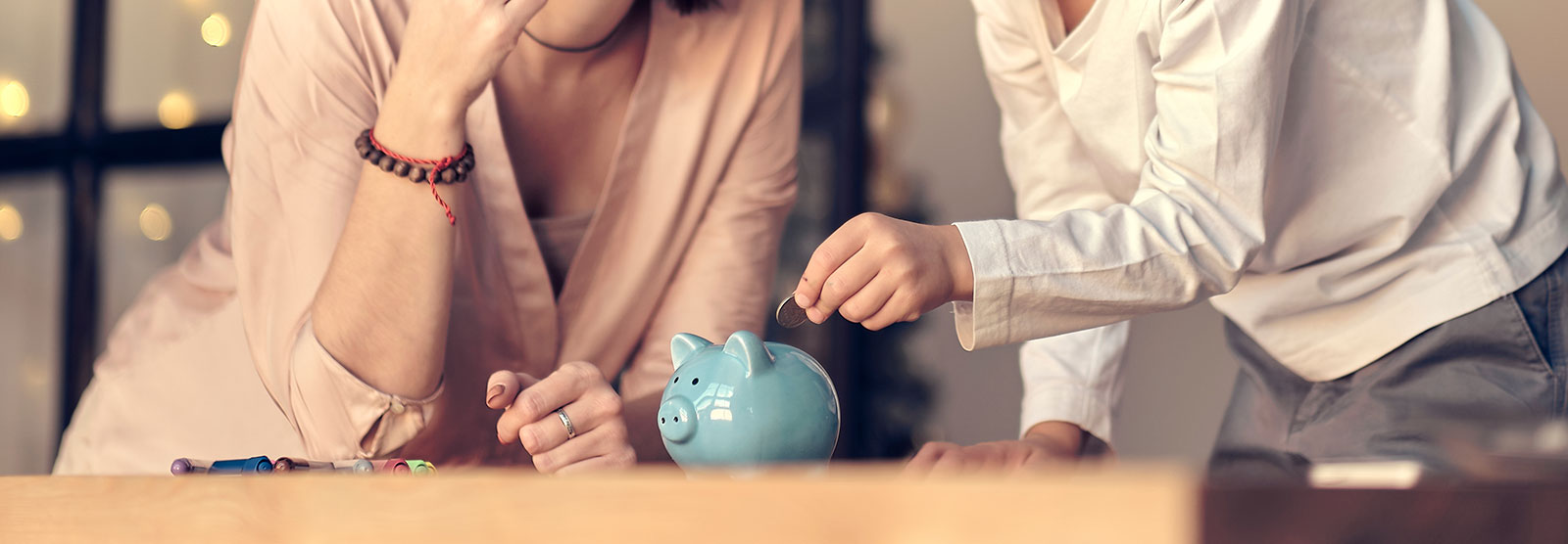 Man and woman standing over piggy bank, putting a quarter in.