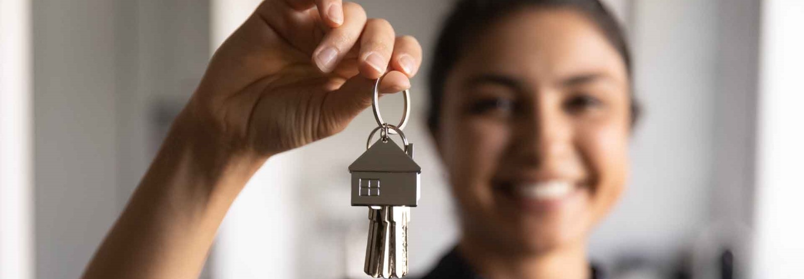 a woman smiling and holding keys to her new home