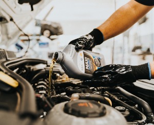 man pouring oil into car.