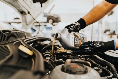 man pouring oil into car.