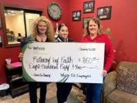 Three women in a room holding a donation check.