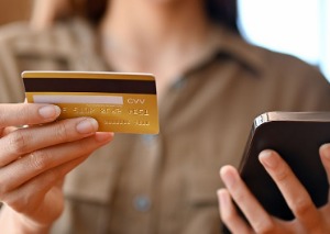 woman holding credit card and phone.