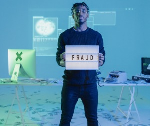 man standing on money holding a sign that says "fraud"