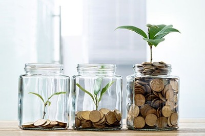 jars lined up with small amount of coins with small plant to full of coins and larger plant.  Grow your money.