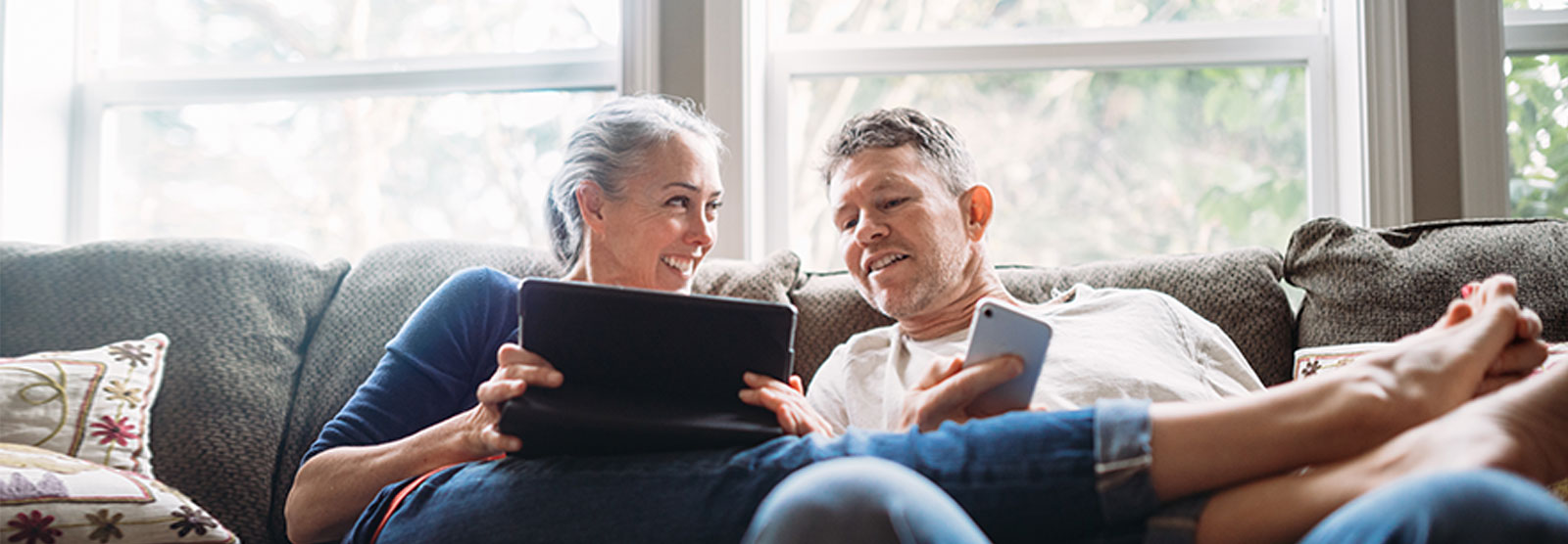 couple on couch looking at laptop and phone.