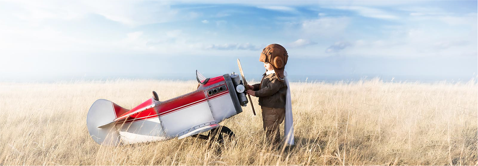 Toddler in aviator outfit and play plane.