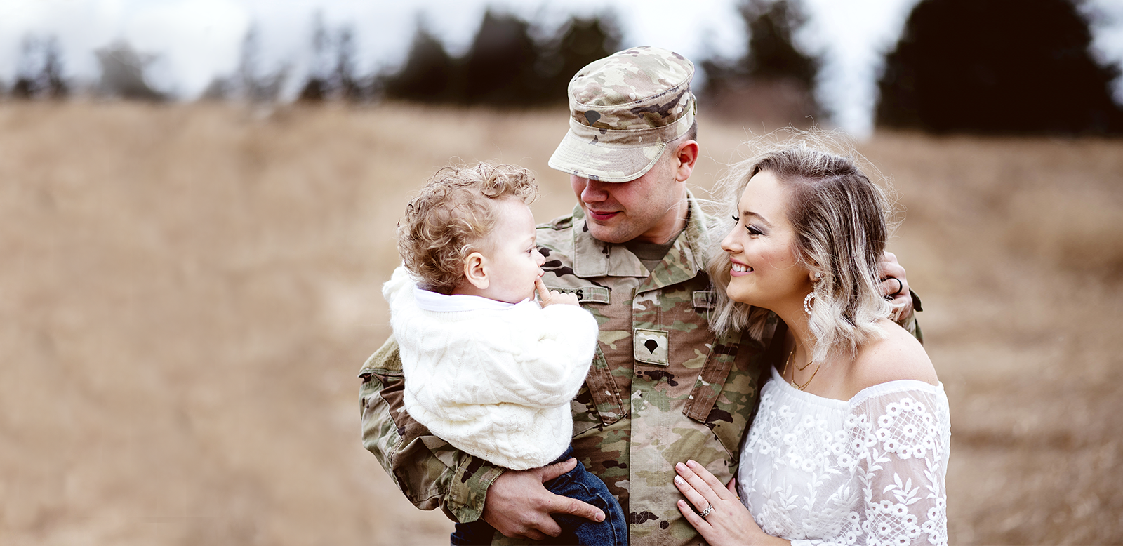 military man and wife holding a baby