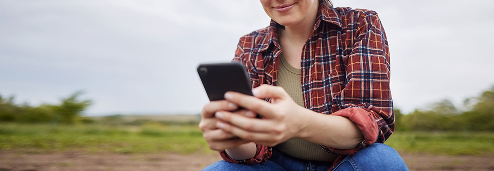 Female farmer checking cell phone on her land.