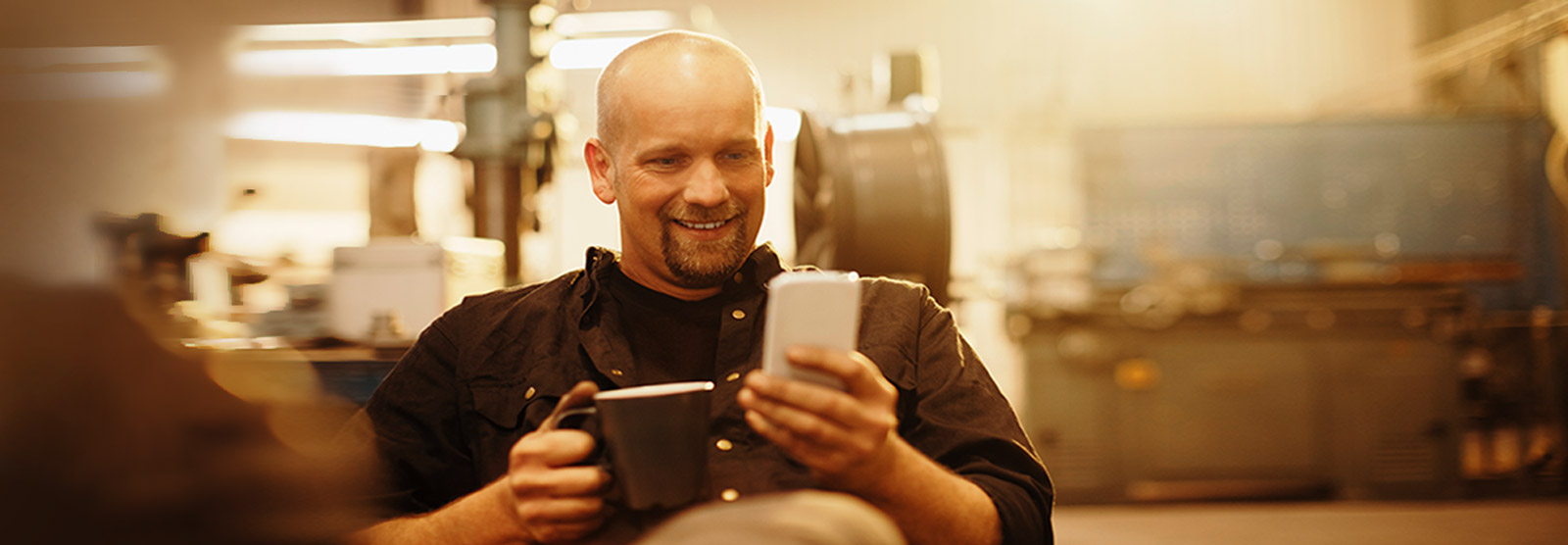 Business owner with coffee checking phone.