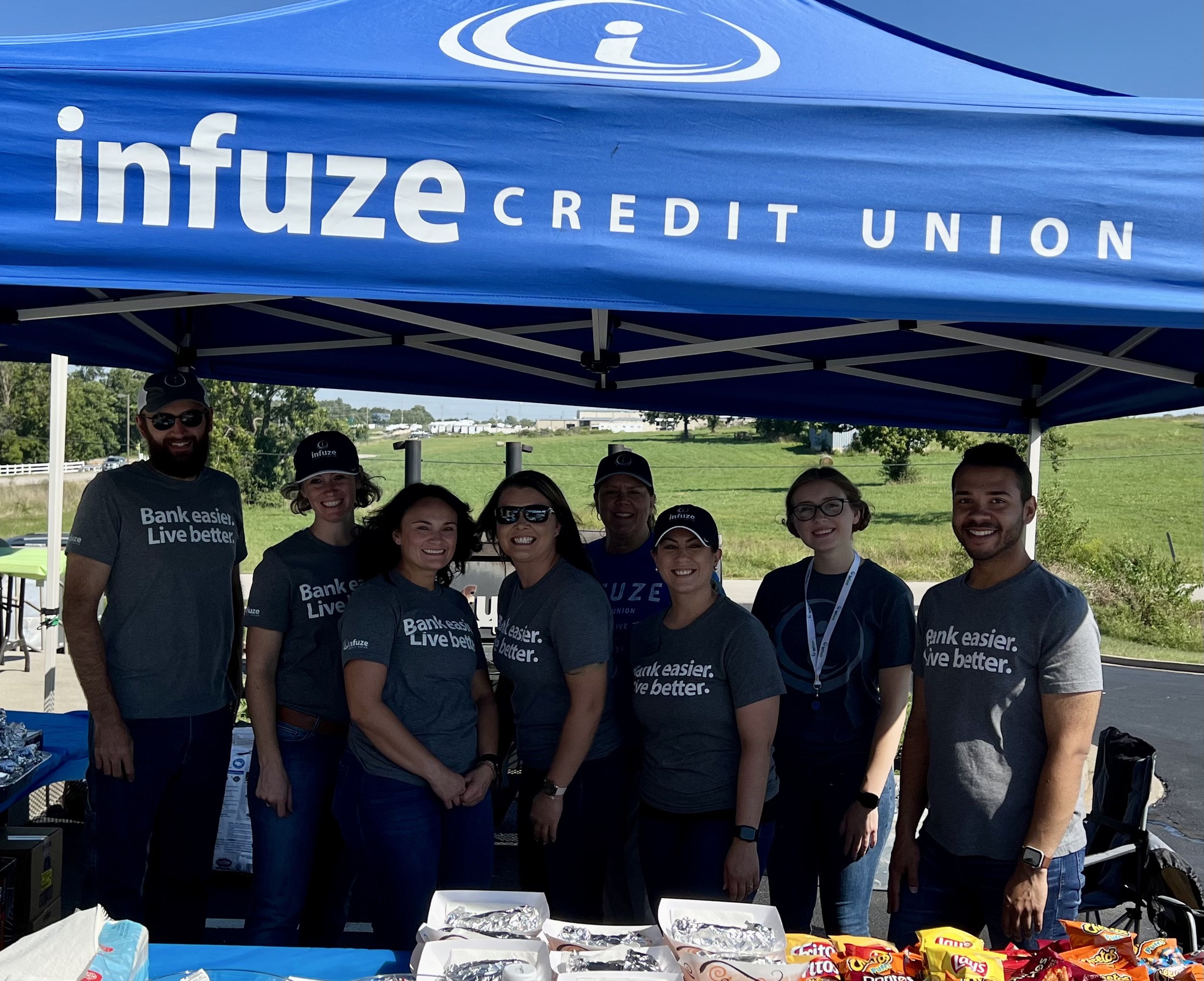Group of people smiling under a canopy.