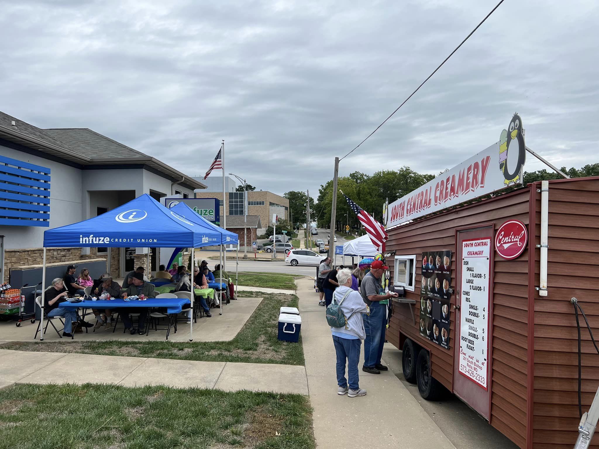 People setting under canopy and getting ice cream.