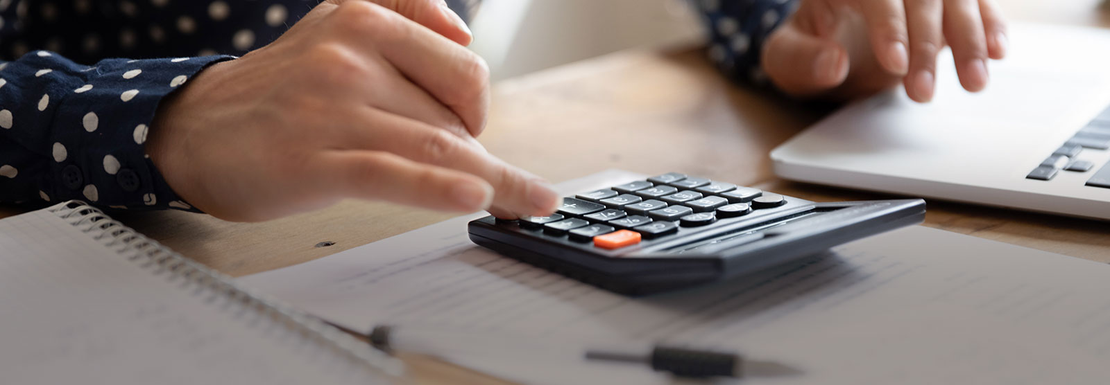 person using calculator on desk with computer